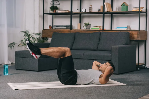 Hombre de raza mixta haciendo ejercicio en la alfombra de fitness en la sala de estar — Stock Photo