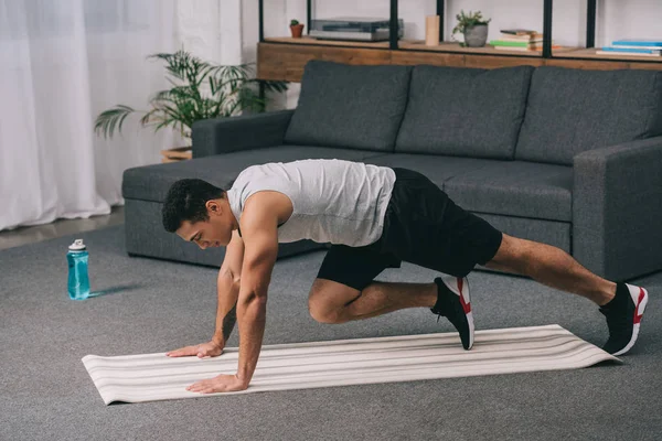 Bi-racial man training on fitness mat in sportswear — Stock Photo