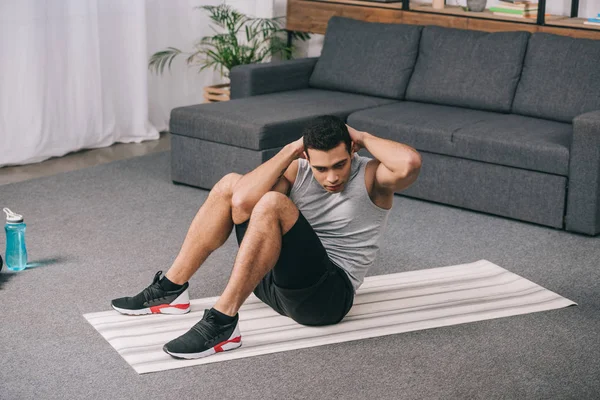 Handsome bi-racial man doing exercise on  fitness mat — Stock Photo