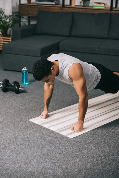 Бирасовый спортсмен отжимается в спортивной одежде на коврике для фитнеса — стоковое фото