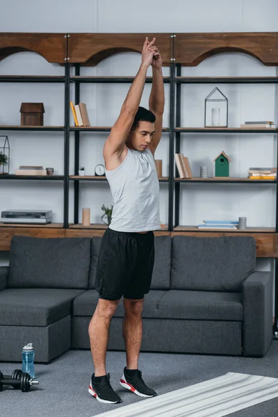 Bonito bi-racial homem de pé perto fitness tapete e fazendo exercício — Fotografia de Stock