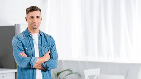 Handsome adult man with crossed arms looking at camera — Stock Photo