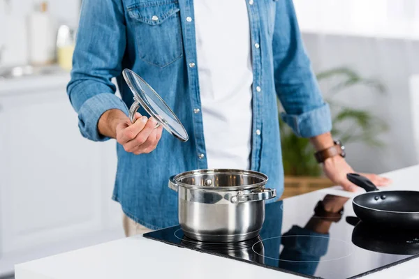 Vista ritagliata dell'uomo che cucina cibo in pentola in cucina — Foto stock