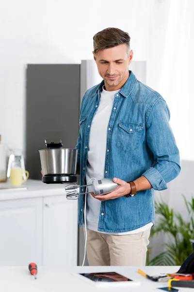 Handsome man repairing kitchen mixer at home — Stock Photo