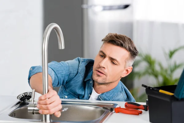 Schöner Mann repariert Wasserhahn der Küchenspüle — Stockfoto