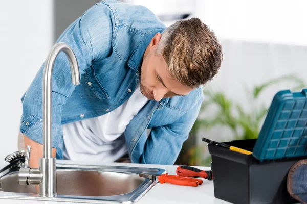 Bel homme réparant évier à la cuisine — Photo de stock