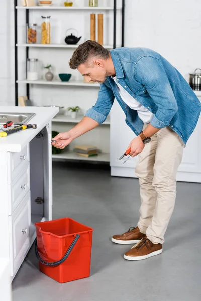 Schöner Mann repariert Spüle mit Werkzeug — Stockfoto