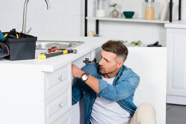 Bel homme réparant évier de cuisine — Photo de stock