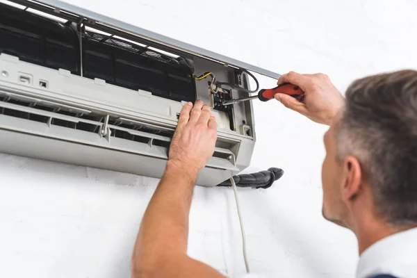 Close up view of adult repairman repairing air conditioner — Stock Photo