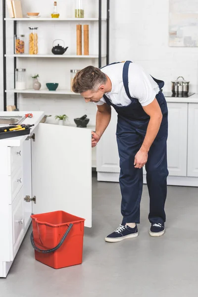 Homme adulte en vêtements de travail réparation évier de cuisine — Photo de stock