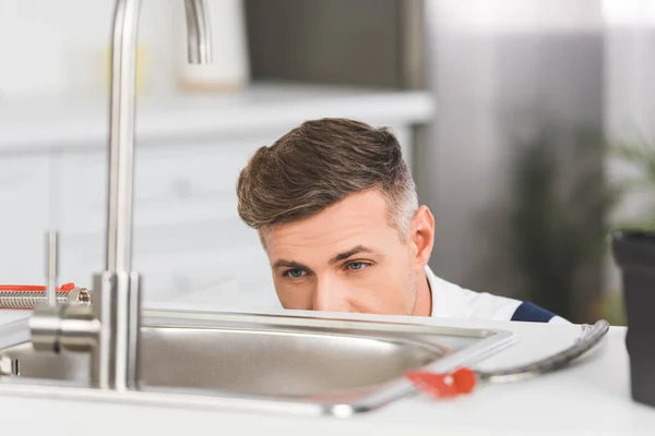 Cropped view of adult repairman looking at sink at kitchen — Stock Photo