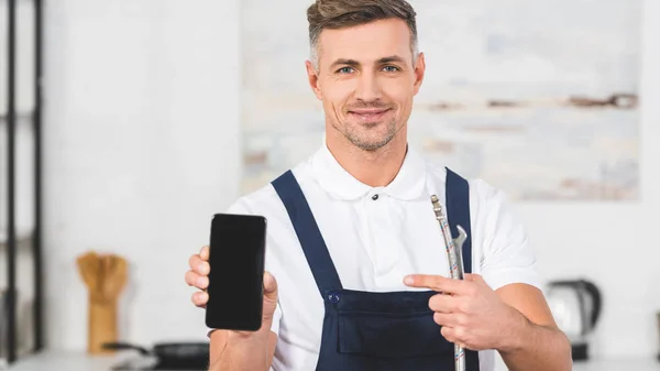 Manitas adultos sonrientes sosteniendo la tubería y apuntando al teléfono inteligente con pantalla en blanco - foto de stock