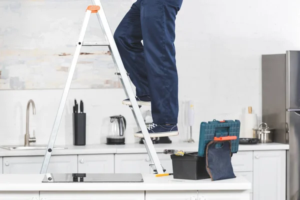 Vista recortada del reparador de pie en la escalera en la cocina - foto de stock