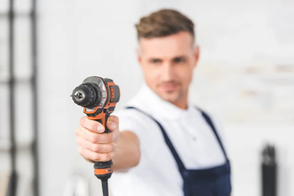 Selective focus of adult repairman holding drill in hand — Stock Photo
