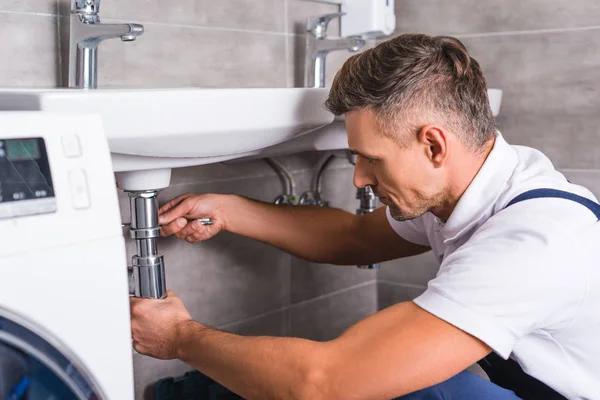 Adult plumber fixing sink at bathroom — Stock Photo