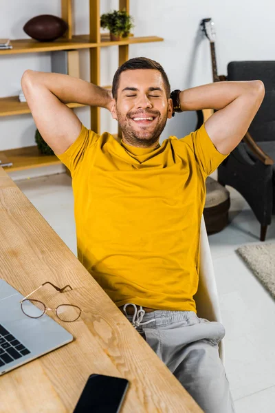Homem alegre sentado na cadeira e sorrindo em casa — Fotografia de Stock