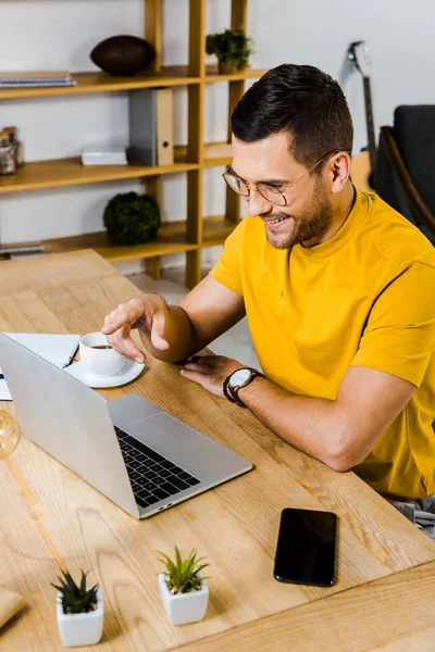 Uomo allegro che punta con il dito al computer portatile a casa — Foto stock