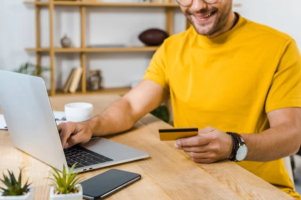 Cropped view of man holding credit card near laptop — Stock Photo
