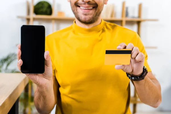 Обрезанный вид человека, держащего смартфон с чистым экраном и кредитной картой в руках — стоковое фото