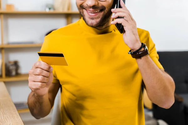 Visão cortada do homem falando no smartphone e segurando cartão de crédito — Fotografia de Stock