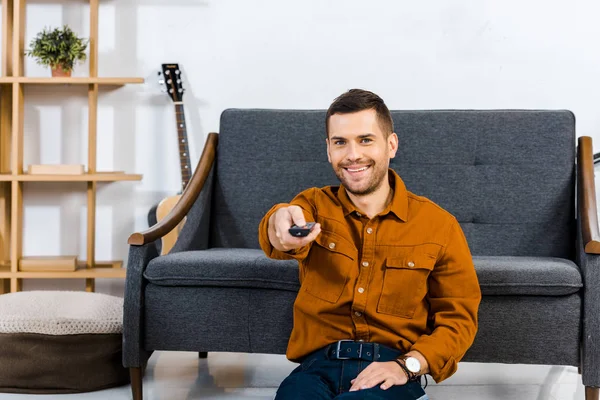 Homem feliz segurando controle remoto em casa — Fotografia de Stock