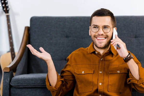 Hombre guapo en gafas hablando en el teléfono inteligente en casa - foto de stock