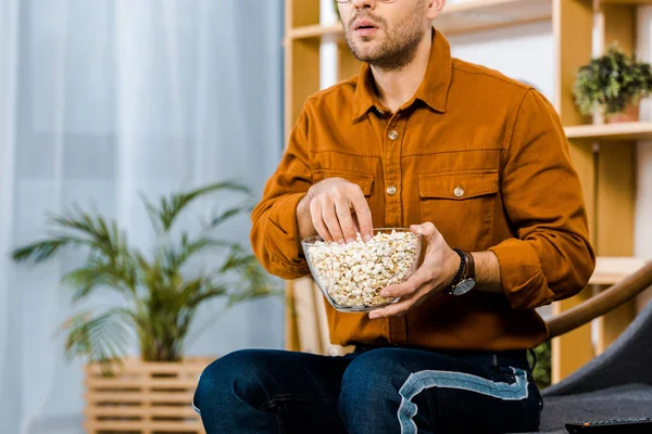 Vista recortada del hombre sorprendido sosteniendo palomitas de maíz en un tazón - foto de stock