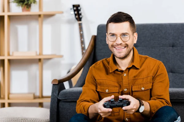 Uomo allegro in possesso di gamepad e giocare al videogioco a casa — Foto stock