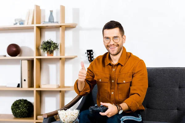 Homem alegre mostrando polegar para cima e segurando gamepad — Fotografia de Stock
