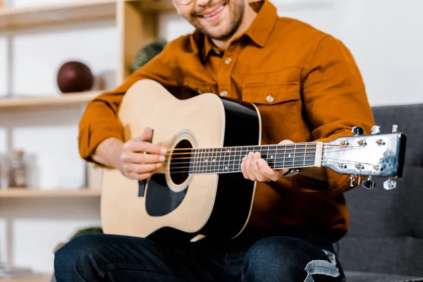 Обрезанный вид веселого человека, играющего на акустической гитаре — стоковое фото