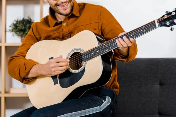 Abgeschnittene Ansicht eines gut gelaunten Mannes mit Brille, der zu Hause Akustikgitarre spielt — Stockfoto