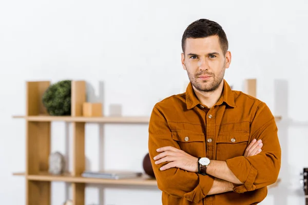 Schöner Mann steht mit verschränkten Armen im Wohnzimmer — Stockfoto