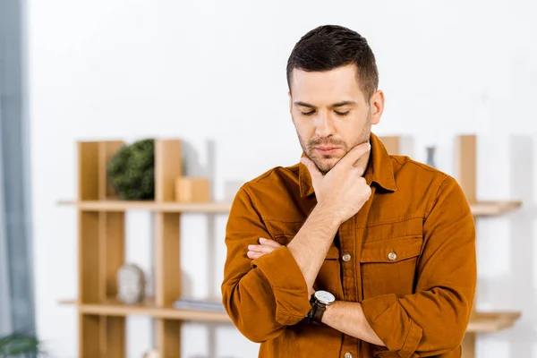 Aufgebrachter Mann macht Denkgeste in modernem Wohnzimmer — Stockfoto