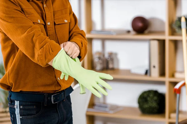 Cropped view of man standing in modern living room putting up rubber gloves — Stock Photo