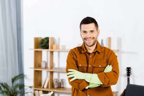 Handsome man standing in modern living room and crossing arms — Stock Photo