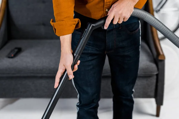 Vista cortada do homem na vida moderna limpeza chão com hoover — Fotografia de Stock