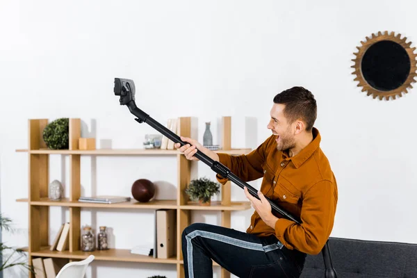 Handsome man in modern living room playing with hoover — Stock Photo
