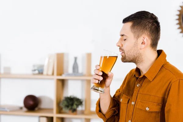 Schöner Mann im modernen Wohnzimmer, der Bier trinkt — Stockfoto