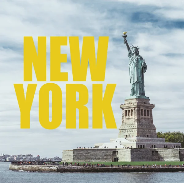 ESTADO DE LIBERTAD, NUEVA YORK, EE.UU. - 8 DE OCTUBRE DE 2018: Estatua de la libertad en Nueva York contra el fondo azul nublado del cielo con letras amarillas de 