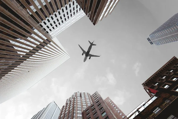 Bottom view of skyscrapers and airplane in cloudy sky in new york city, usa — Stock Photo