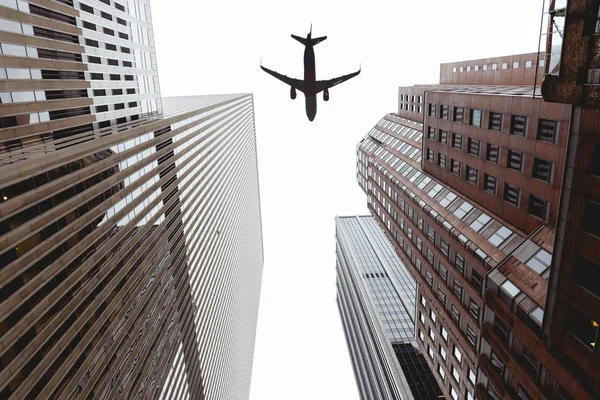 Vista inferior de rascacielos y cielo despejado con avión en la ciudad de Nueva York, EE.UU. - foto de stock