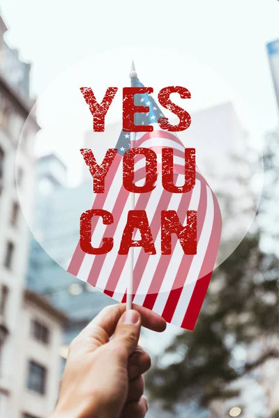 Cropped shot of man holding american flag in hand with blurred new york city street on background and 