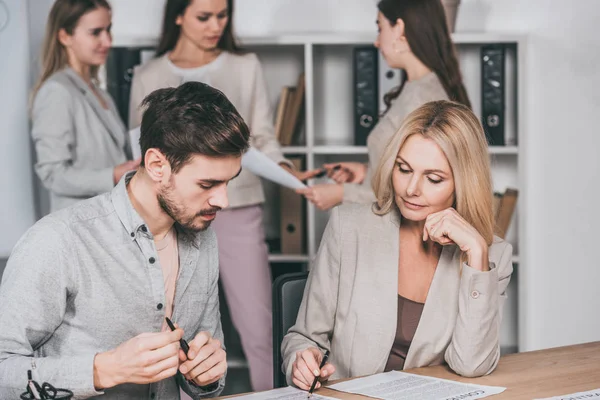 Professional mentor working with young businessman, businesswomen standing behind in office — Stock Photo