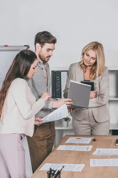 Konzentrierte professionelle Geschäftsleute, die mit Papieren arbeiten und das Projekt im Büro diskutieren — Stockfoto