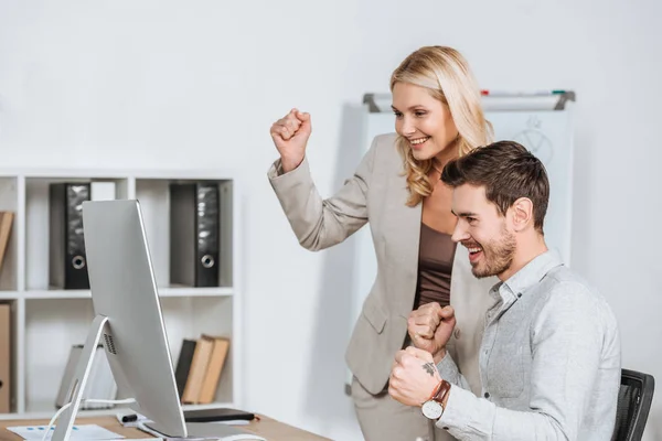 Empresários profissionais alegres triunfando e usando computador desktop no escritório — Fotografia de Stock