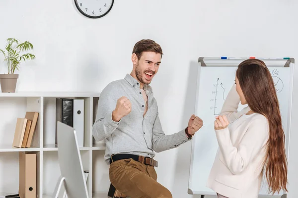 Eccitati giovani colleghi d'affari trionfare insieme sul posto di lavoro — Foto stock