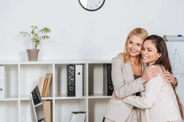 Schöne, glückliche Geschäftsfrauen, die zusammenstehen und im Büro wegschauen — Stockfoto