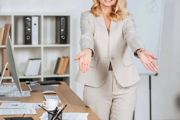 Recortado disparo de sonriente mujer de negocios saludando a alguien y haciendo un gesto con las manos en la oficina - foto de stock