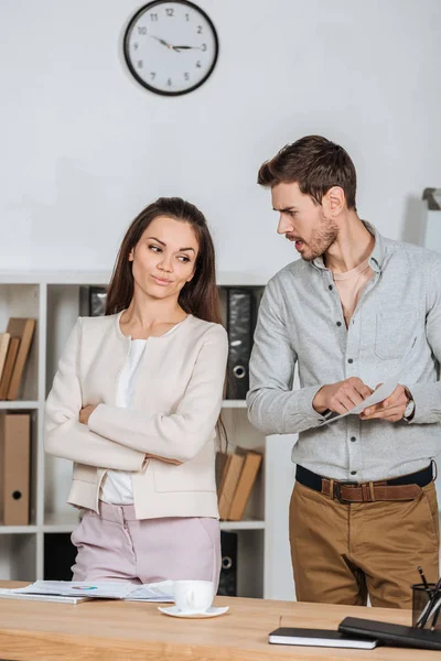 Wütender Geschäftsmann mit Dokument und Schreien und Geschäftsfrau mit verschränkten Armen — Stockfoto