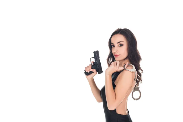 Hermoso agente de seguridad en vestido negro con pistola y esposas, aislado en blanco - foto de stock